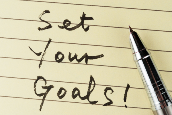 Set your goals words written on lined paper with a pen on it.