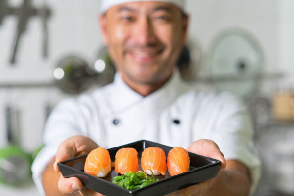 Smiling Asian chef with sushi.